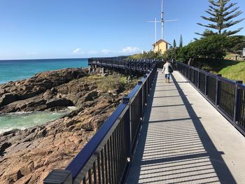 Footbridge over sea against sky