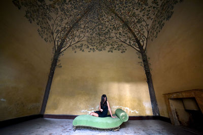 Woman sitting on sofa against wall