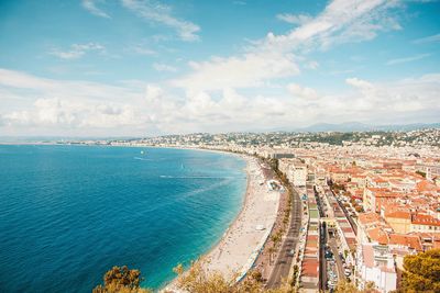 High angle view of townscape by sea against blue sky
