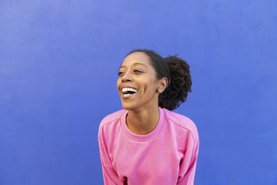 Cheerful woman with afro hairstyle in front of blue background