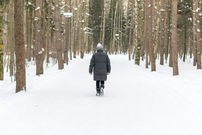 Rear view of person walking on snow covered landscape