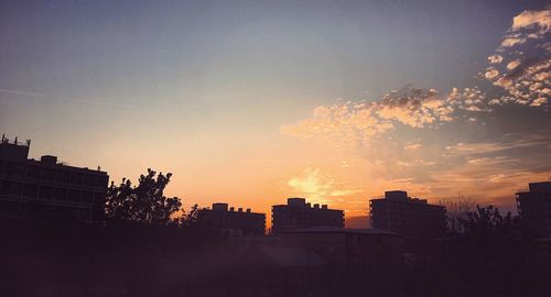 Low angle view of silhouette buildings against sky at sunset