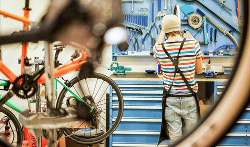 Rear view of man standing at bicycle shop