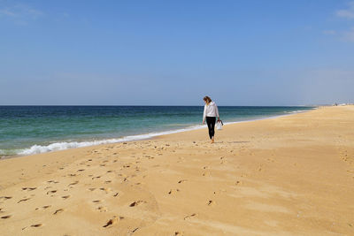 Woman standing on beach against clear sky