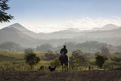 People riding horse on field against sky