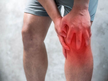 Digital composite image of man holding knee in pain