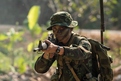 View of soldier holding rifle standing outdoors