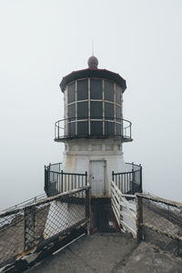 Lighthouse by sea against clear sky