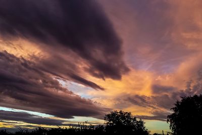 Low angle view of silhouette trees against dramatic sky