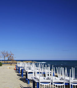 Chairs on beach against clear blue sky