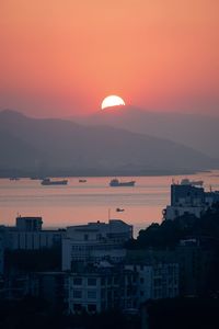 Silhouette buildings against orange sky at sunset