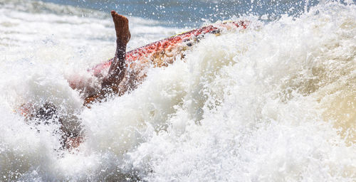 Waves over person surfboarding on sea