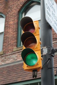 Low angle view of gree traffic light against building