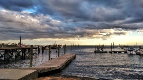 Pier on sea against cloudy sky