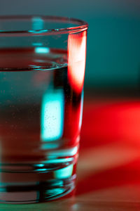 Macro shot of glass of water in red blue trendy neon light.