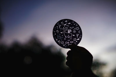 Close-up of hand holding bubbles against sky