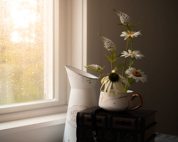 Flower vase on table by window at home