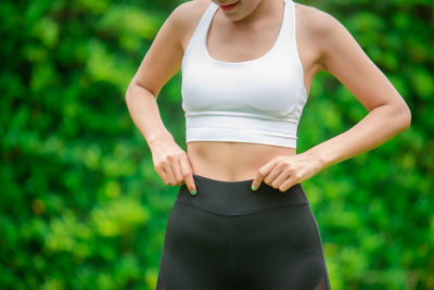 Midsection of young woman standing against blurred background