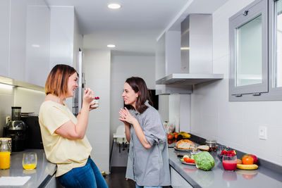 Cheerful women talking while standing in kitchen