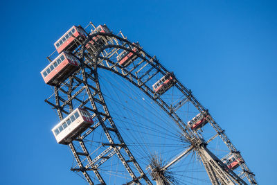 Low angle view of ferris wheel against clear blue sky