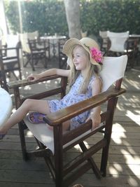 Smiling girl sitting on chair at sidewalk cafe 