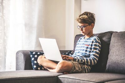 Full length of boy using laptop at home