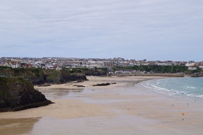 Scenic view of beach by buildings against sky