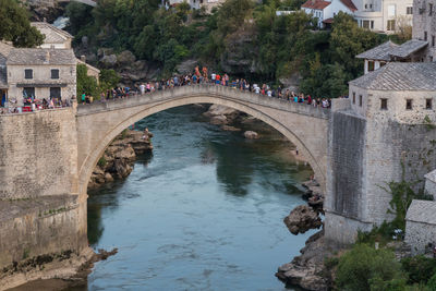 People on bridge over canal against sky