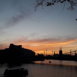 Silhouette bridge over river against sky during sunset