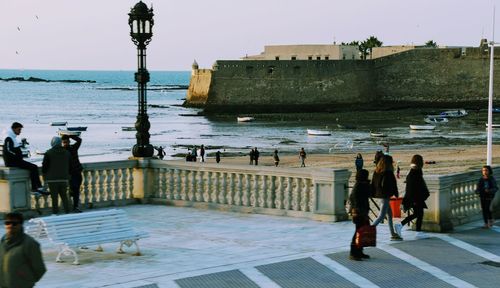 People standing by sea against sky