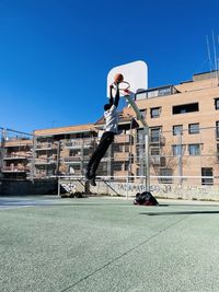 Sunny day at the madrid spain city sport instalación man play street basket jumping high doing smash 