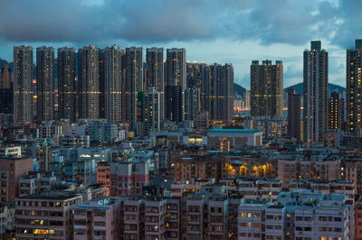 Illuminated modern buildings in city against sky