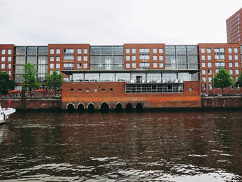 Arch bridge over river by buildings against sky in city