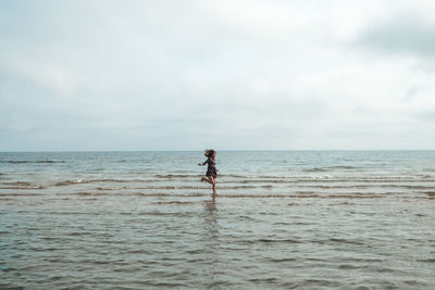 Woman running on beach against sky