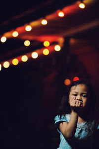 Portrait of girl against illuminated lights at night