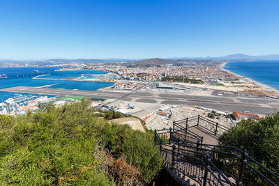 High angle view of townscape by sea against blue sky