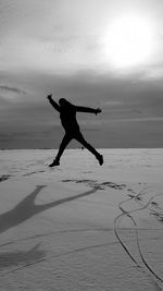 Man jumping on beach against sky