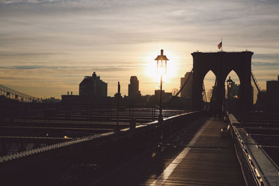 Brooklyn bridge against sky in city during sunset