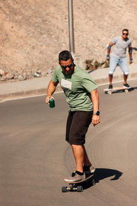 Two men playing figure skating on a rural road in the sun on a bright day,play surf skate near coast