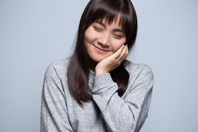 Smiling young woman against gray background