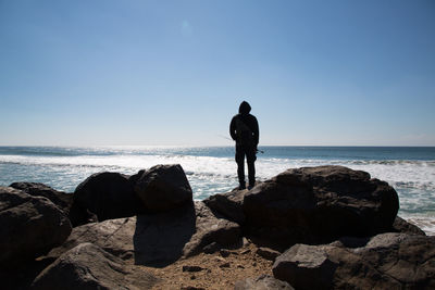 Man fishing in sea against sky