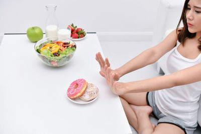 Woman gesturing stop sign against food at home