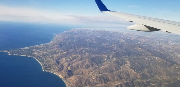 Aerial view of aircraft wing over landscape against sky