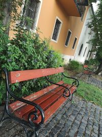 Empty bench by potted plant outside house in yard