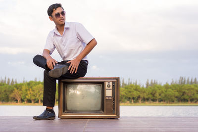 Young man with camera against sky