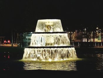 Water fountain in sea against sky at night