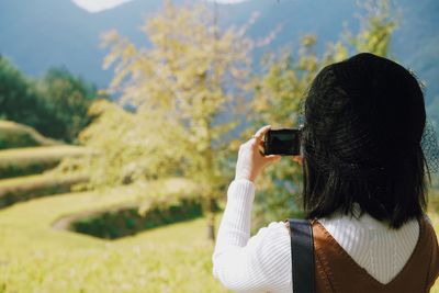 Rear view of man photographing camera on mobile phone