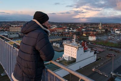 Woman standing by cityscape against sky