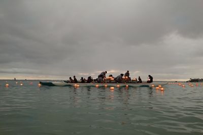 Boat in sea against cloudy sky