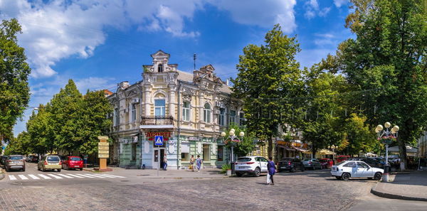 Cars on street by buildings against sky in city